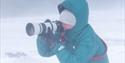 A person taking a picture in stormy weather.