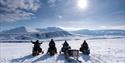 Gruppe på snøscootere på åpent, snødekt platå.