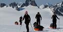 En turgruppe som drar pulker på ski