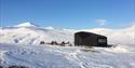 Krekling Lodge and a couple of snowmobiles parked in front of the cabin