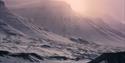 A person on a snowmobile in a landscape with mountains in the background