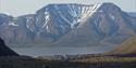 The mountain Hiorthfjellet in the background with the fjord Adventfjorden, Longyearbyen and rocky terrain in the foreground.