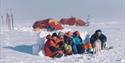 A tour group sitting huddled up together in a tent camp