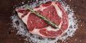 A piece of meat with garnish laying on a table with salt spread on top of it