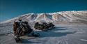 Three snowmobiles out in the wilderness beneath starry skies