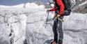 A person with glacier safety equipment standing on a glacier
