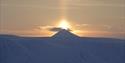 The midnight sun shining behind a mountain peak