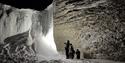 A group of people standing with headlamps, lighting up the frozen waterfall