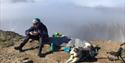 A person and a dog having a lunch break on the top of Sarkofagen