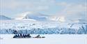 Snowmobiles in front of a glacier