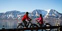 A guide and a guest on bikes with mountains in the background