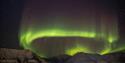 A circle of northern lights in the skies above a mountain range