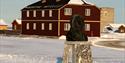 A metal bust of Roald Amundsen in the centre of Ny-Ålesund, with buildings and snowy streets in the background