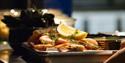 A dinner plate with shrimp, lemon and other food on kitchen counter