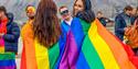 Two persons using pride flags as capes on their backs