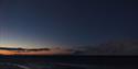 A beautiful sunset, with organs and blue light, and mountains to the right in the picture