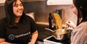 Two persons looking at each other while cooking a meal on a stove.