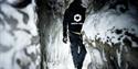 A person walking in the narrow ice cave.