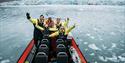 Several people in open RIB. glacier seen in the background
