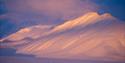 Snow-covered mountain, with the sunlight shimmering on it.