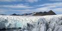 Glacial crevasses and ice faces with mountains in the background