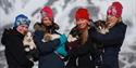 Four people pose in front of a mountain formation, each holding a puppy in their arms.