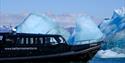 A boat sailing along a line of icebergs in a fjord