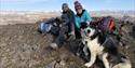 Two persons and a dog relaxing on top of a mountain