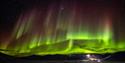 Northern lights shining in the skies above an open valley