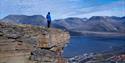 person standing on mountaintop looking at the view over town