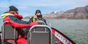 A guide explaining something to a guest on board a RIB boat