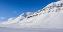 Deltakere på Svalbard Skimaraton i skiløypa med fjell i bakgrunnen