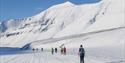 Deltakere på Svalbard Skimaraton i skiløypa med fjell i bakgrunnen