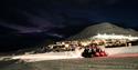 Snøscootere står på med Longyearbyen i bakgrunnen