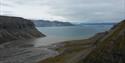 A fjord surrounded by mountains with a river delta in the foreground