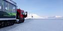 A snowcat in front of a polar bear warning sign