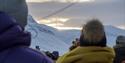 Persons waiting for the sun to rise above a mountain to shine down on Longyearbyen