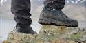 Person standing on rocks with dirty hikingboots. 
Only the shoes are visible in the picture