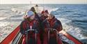 A group of guests on board a RIB boat sailing at speed in a fjord