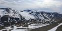 Et lett snødekt fjellandskap med en isbre og en skyet himmel i bakgrunnen