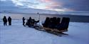 Guests next to a snowmobile enjoying the view across a fjord