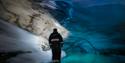 Person standing inside the blue icecave