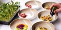 A person preparing food dishes in bowls on a tabletop