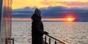 Person on board a boat, looking at the sunset