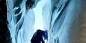 person climbing down an icecave with the help of a safety rope.