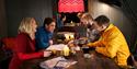 Four guests sitting around a table looking at a map of Svalbard in a room with dimmed lights