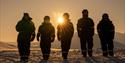 A group of people walking in a snowcovered landscape during sunset