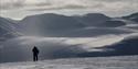 A person standing alone looking out across a snow-covered landscape in the background