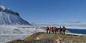 People on a small mountain looking out in the nature with snowcovered grounds and mountain in the background
