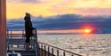 Person onboard a boat, looking at the sunset